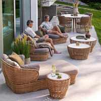Stylish outdoor furniture featuring natural rattan weave, soft gray cushions, and round white tabletops, perfect for patio decor.