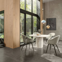Elegant modern dining room with neutral tones, wood textures, and patterned chairs, featuring a round white table.