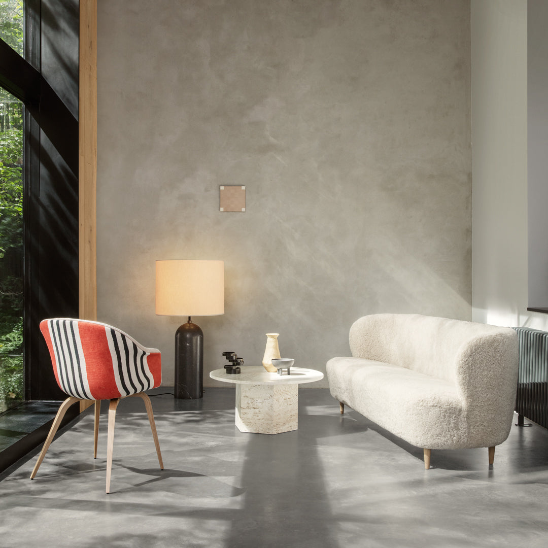 Stylish living room with a cream sofa, striped red and white accent chair, and warm wooden tones. Modern decor with natural light.