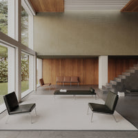 Modern interior featuring black chairs, white rug, and earthy wood accents with a minimalist, neutral palette.