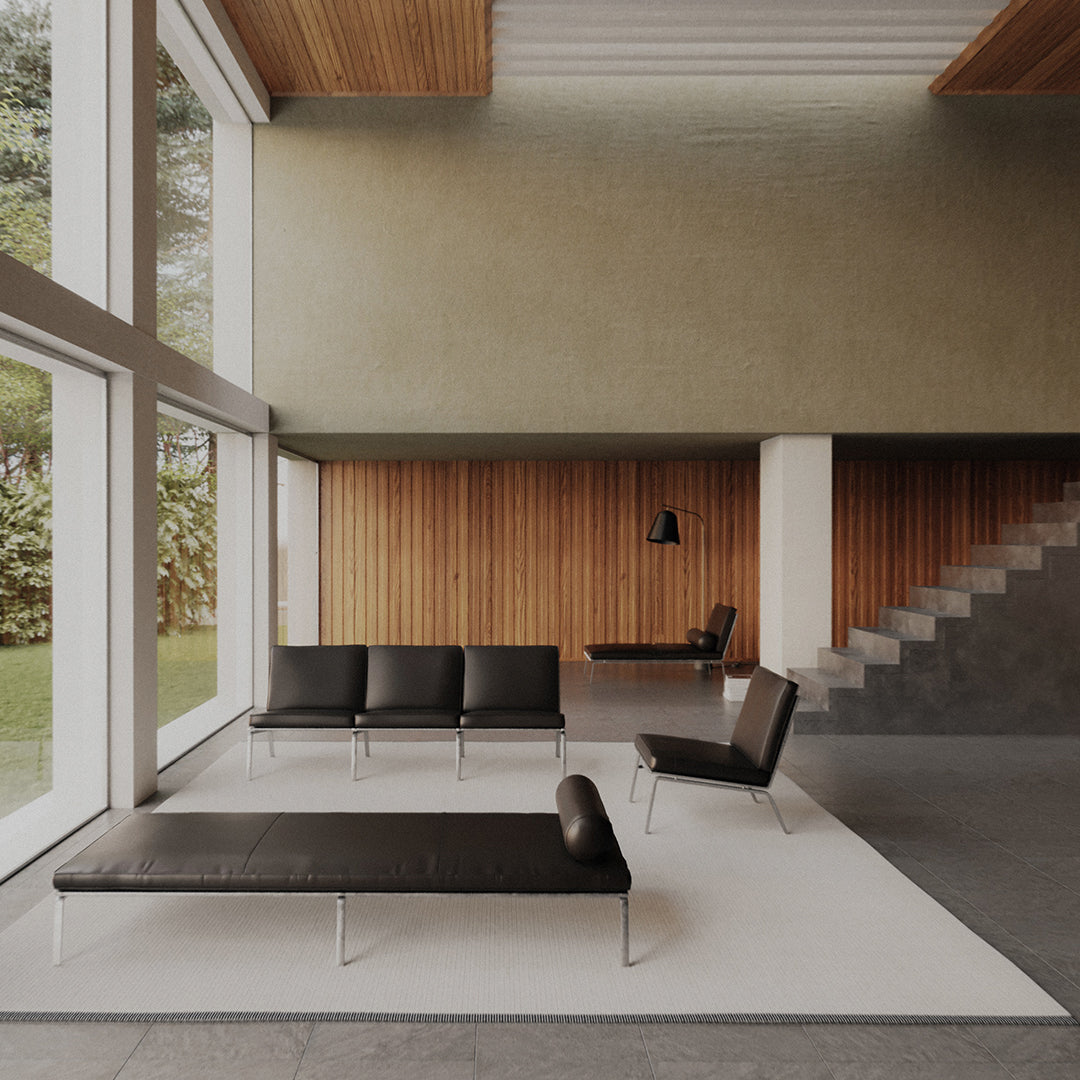 Modern minimalist lounge area featuring sleek black furniture against a light gray and warm wood backdrop.