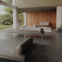Modern outdoor lounge with earthy tones, neutral gray cushions, and a sleek wood-paneled backdrop.