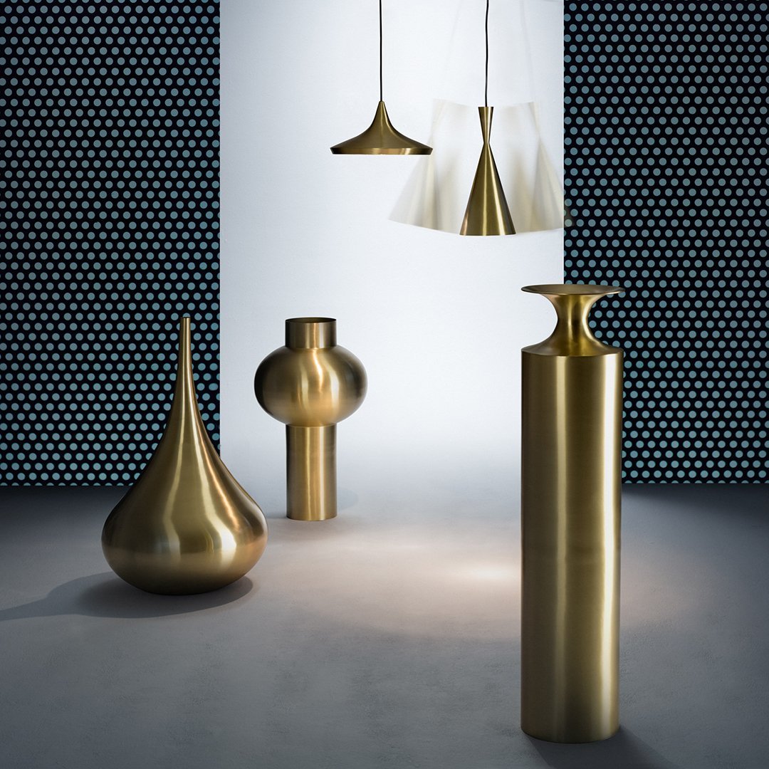 "Brass decor pieces with unique shapes, set against a contrasting blue dotted wall, creating an elegant ambiance."