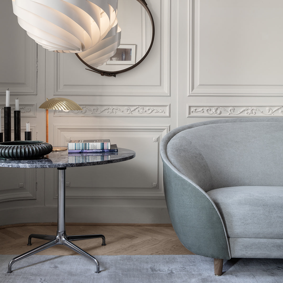Modern gray sofa with curved design, marble table, and clean, neutral tones creating a stylish living space.