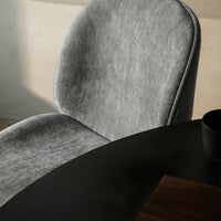 Soft gray upholstered chair with a smooth, rounded design beside a dark wooden table.