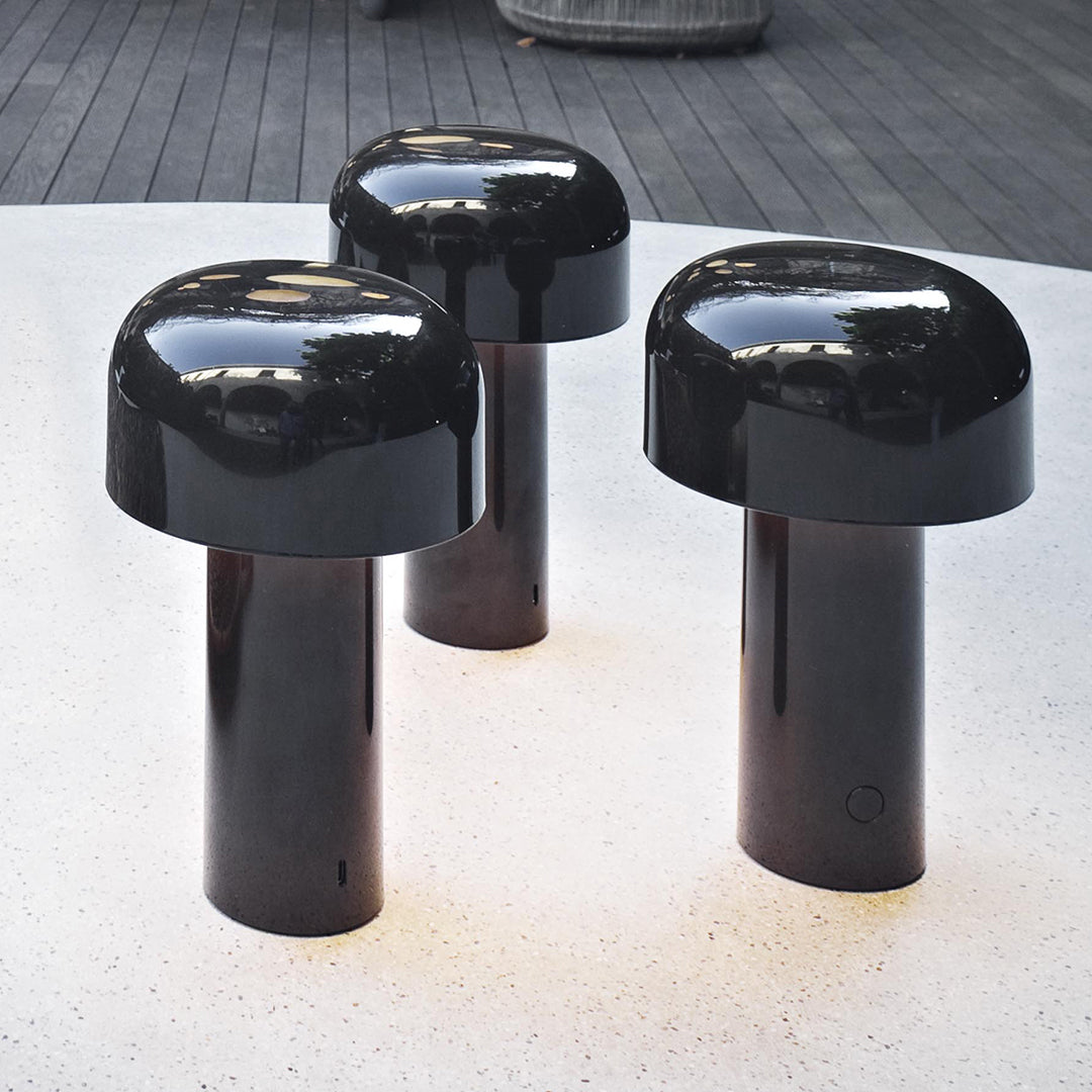 Glossy black mushroom-shaped stools with sleek cylindrical bases, perfect for modern decor.