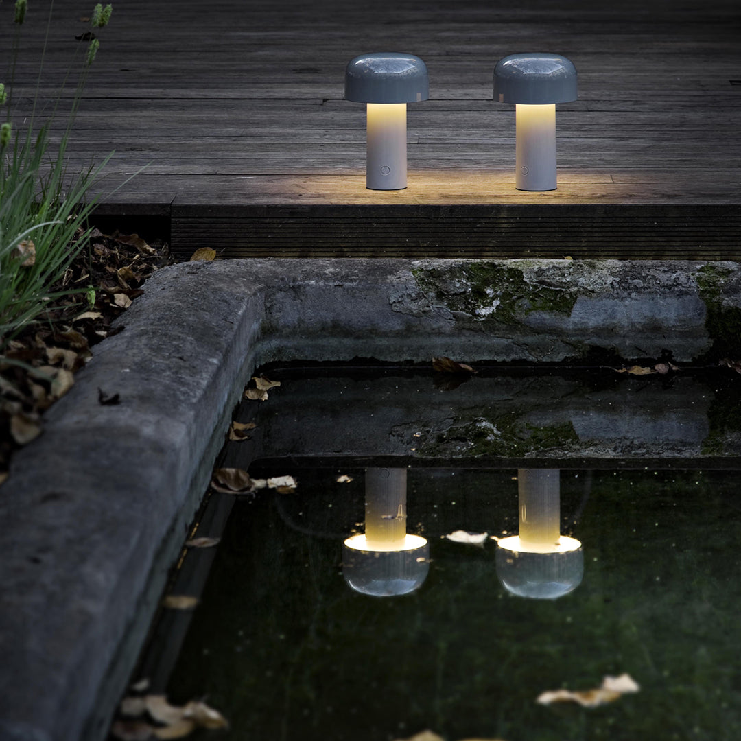 Two sleek gray and white lamps reflecting in a serene pond, highlighting their modern design and soft lighting.