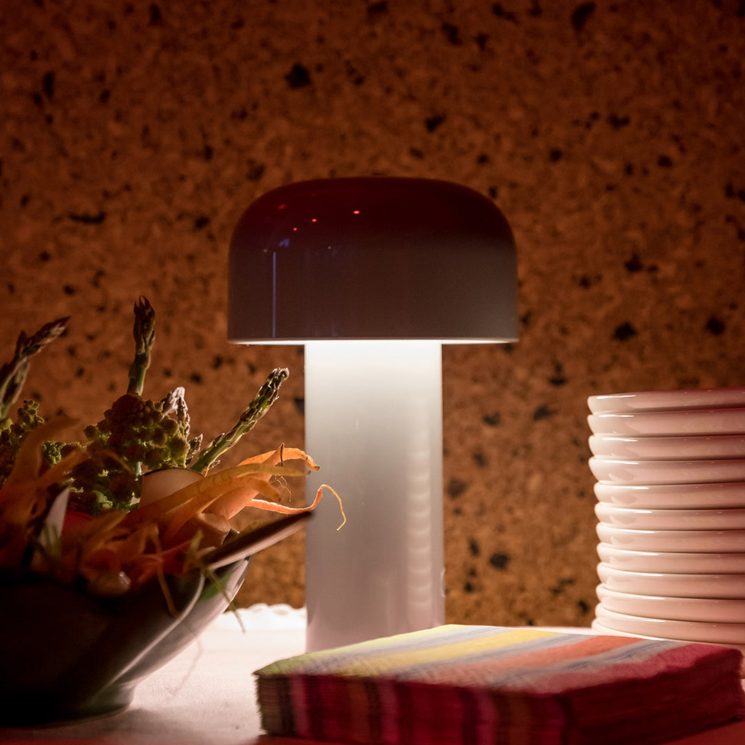Modern mushroom-shaped lamp with a dark brown top and white base, complemented by colorful striped napkins.