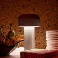 Modern mushroom-shaped lamp with a dark brown top and white base, complemented by colorful striped napkins.