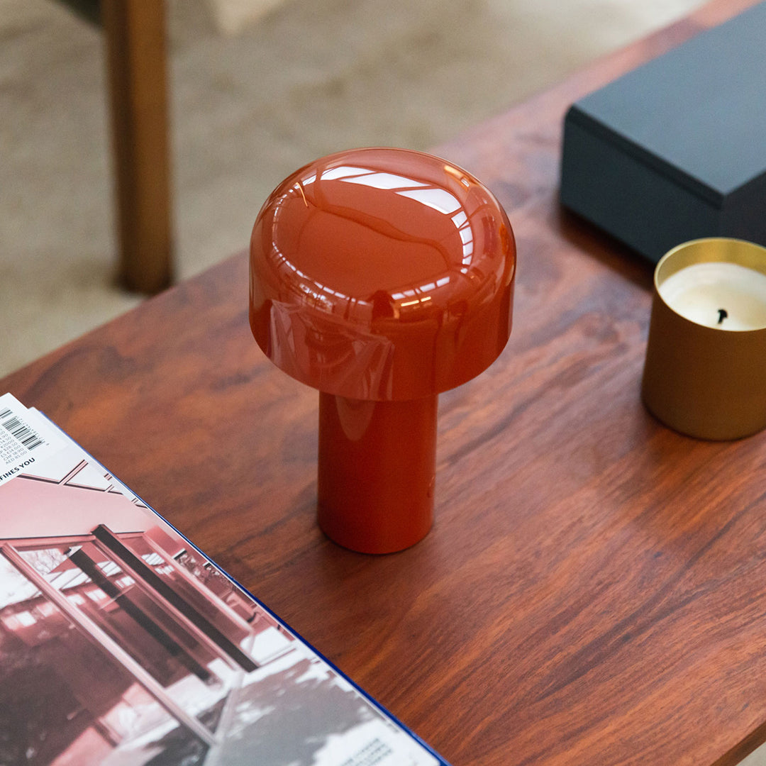 Glossy terracotta mushroom lamp on a wooden table, complementing minimalistic decor with warm tones.