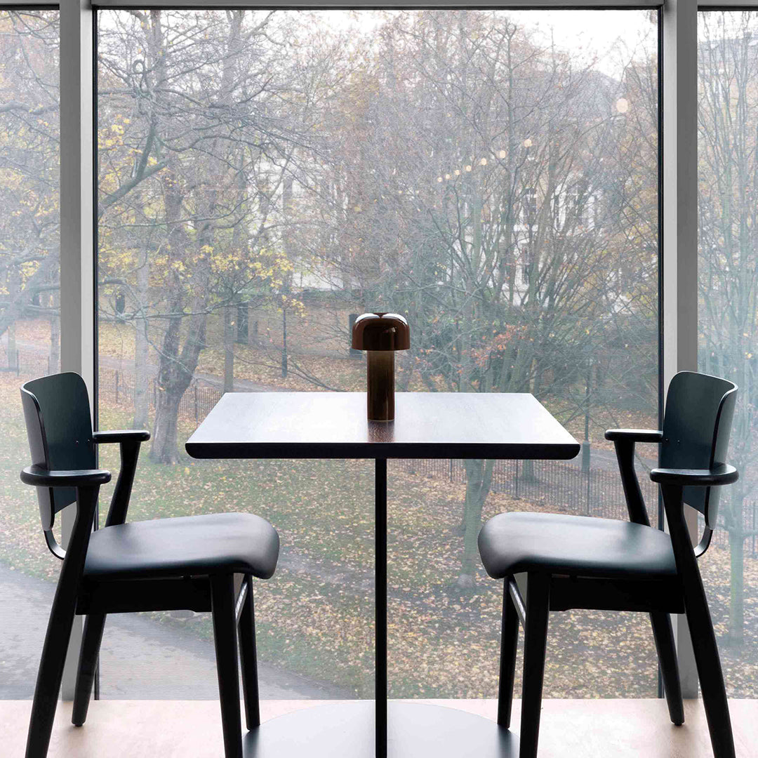 Modern black table with sleek design, complemented by stylish black chairs against a foggy outdoor backdrop.