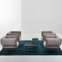 Gray and beige modern chairs on a blue textured rug, complemented by sleek black tables.