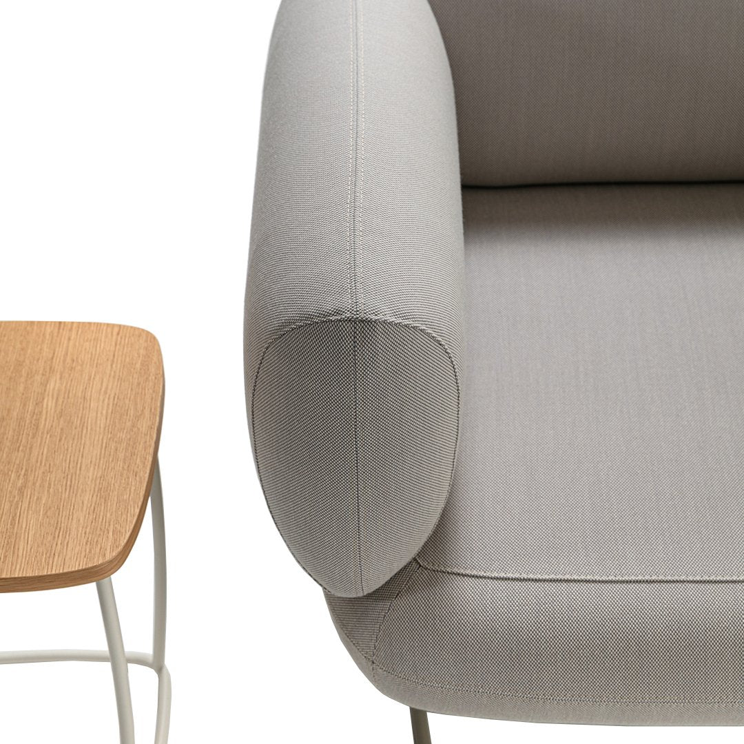 Gray upholstered armchair with smooth texture, paired with a natural wood side table in a minimalist style.