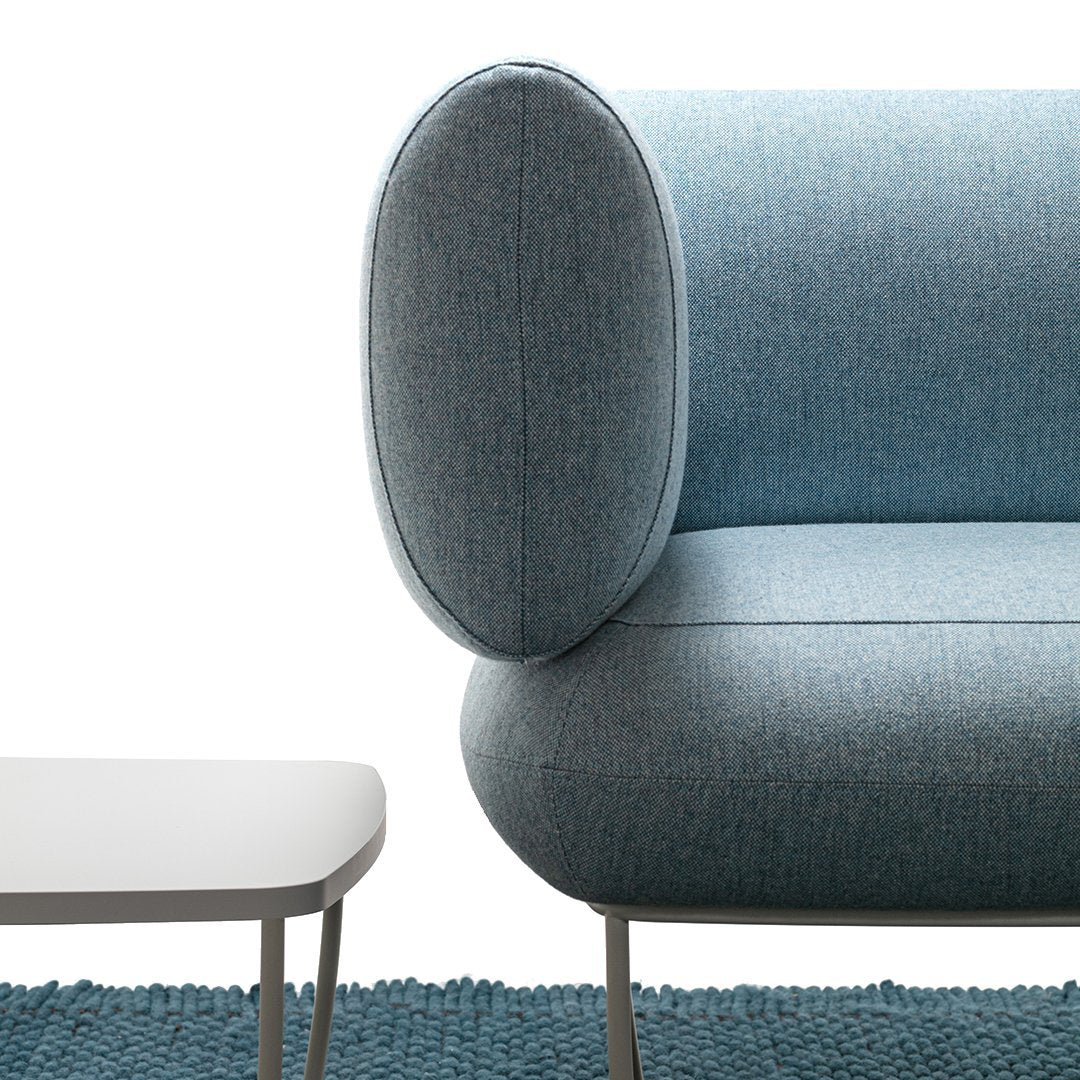 "Light blue sofa with rounded armrest, featuring a textured fabric and paired with a simple white coffee table."