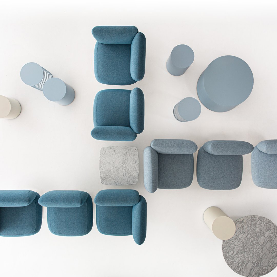 Soft blue upholstered chairs and light gray accent tables on a white background. Modern, minimalist design.