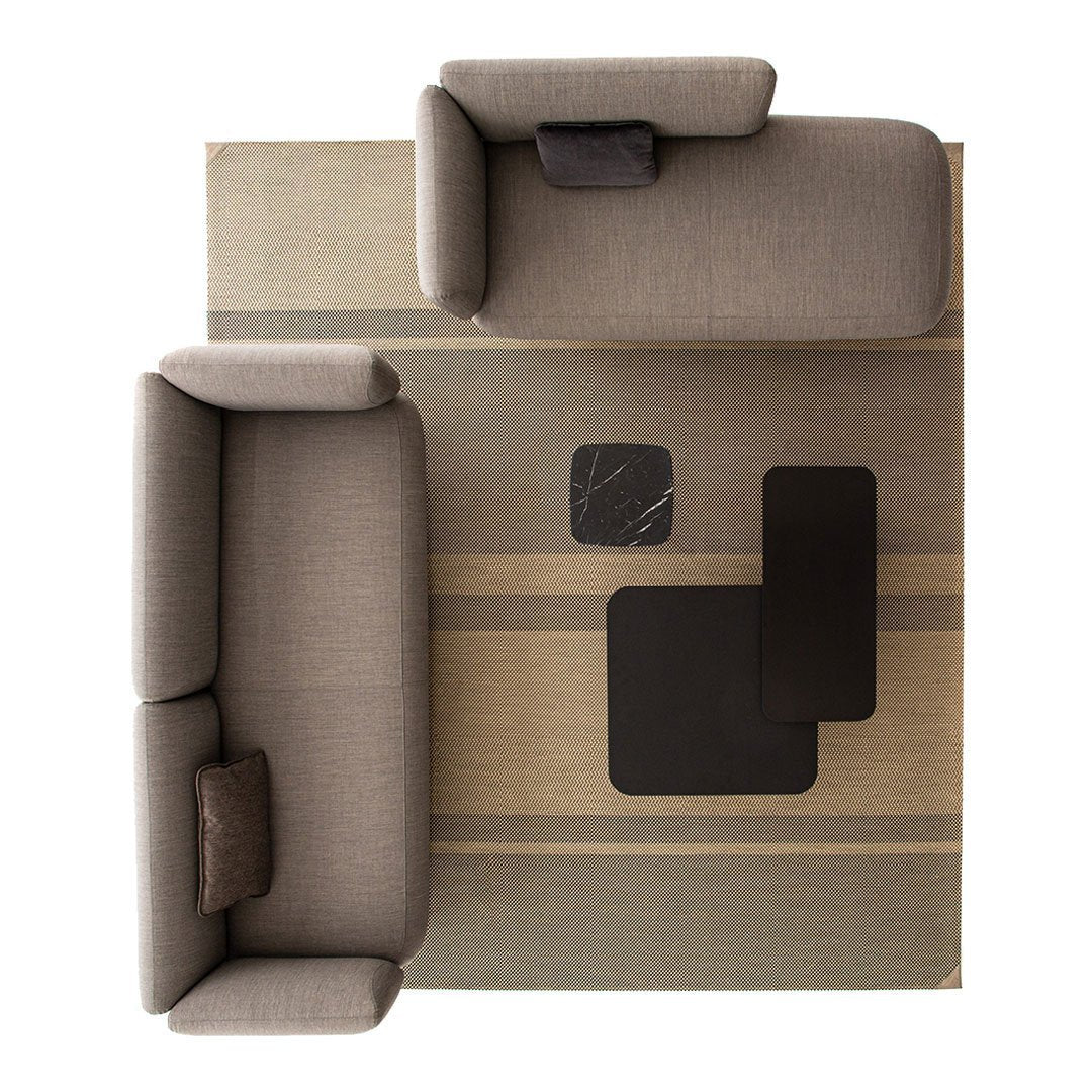 Gray upholstered sofas on a beige and gray striped rug with black accent tables. Modern, minimalistic design.