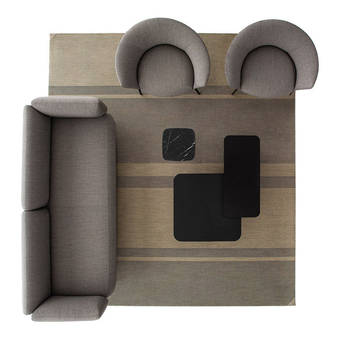 Gray sofa and chairs on a striped beige and gray rug, featuring black accent tables for a modern look.