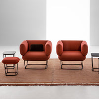 Rust orange armchairs with circular backs, set on a textured brown rug, paired with black and red accent tables.