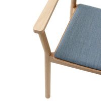 Light wood armchair with a textured blue fabric cushion, showcasing a minimalistic and contemporary design.
