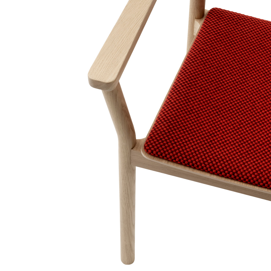 Red and black checkered seat cushion with natural wood armrest and frame. Modern design and vibrant color contrast.