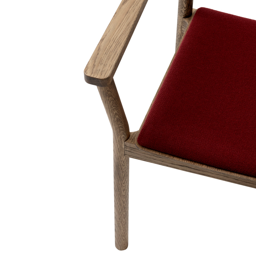 Red upholstered chair with a natural wood frame, showcasing minimalist design and rich color contrast.