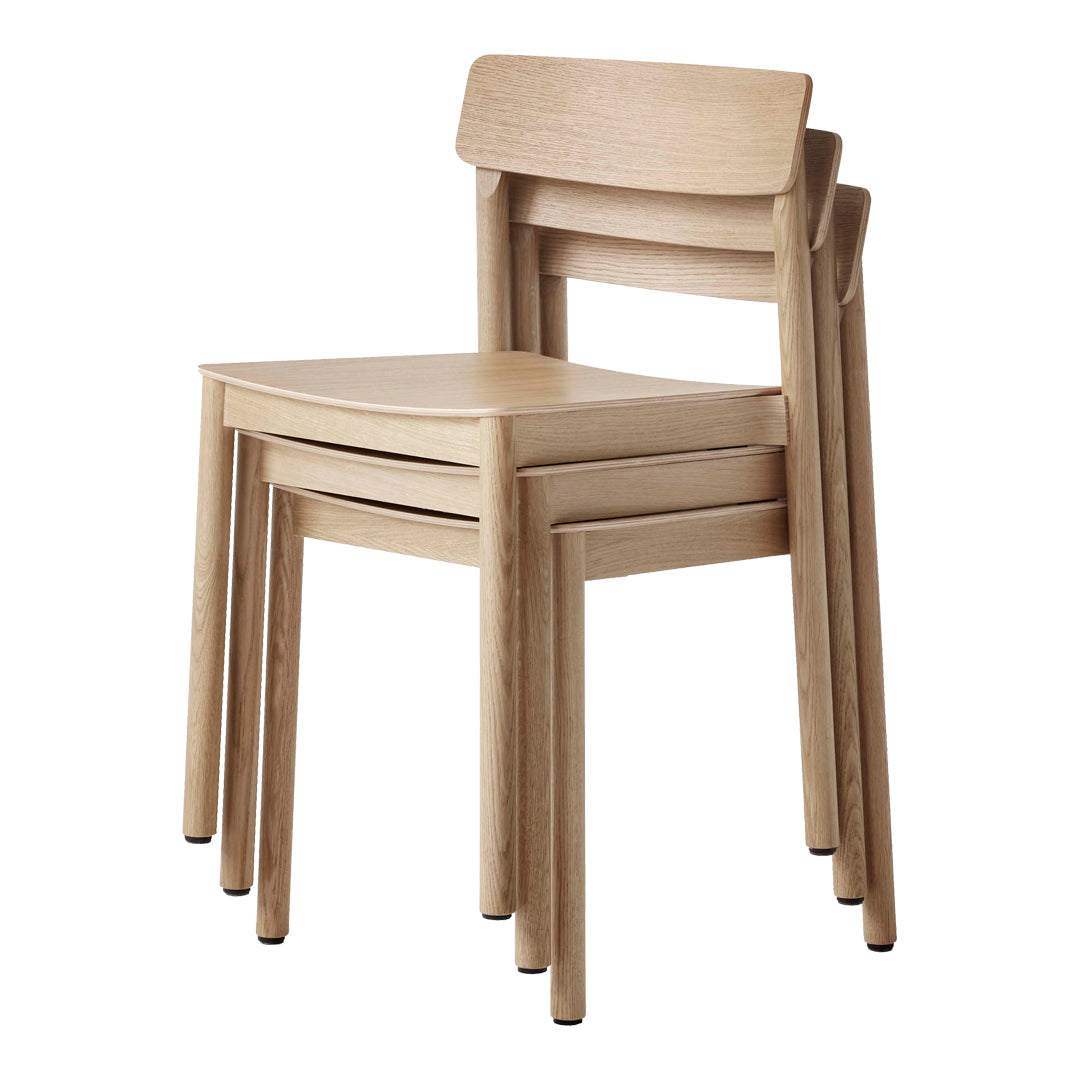 Stacked wooden chairs in a natural, light finish with smooth lines and a minimalist design.