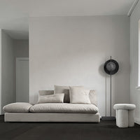 Elegant light gray fabric sofa with soft pillows, complemented by minimalistic black and white accents in a modern interior.