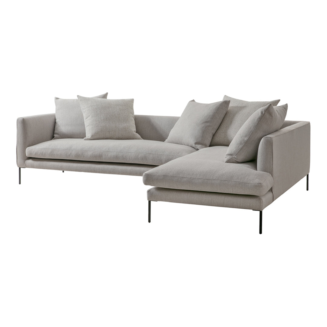 Light gray sectional sofa with a minimalistic design and soft, textured fabric, complemented by matching pillows.