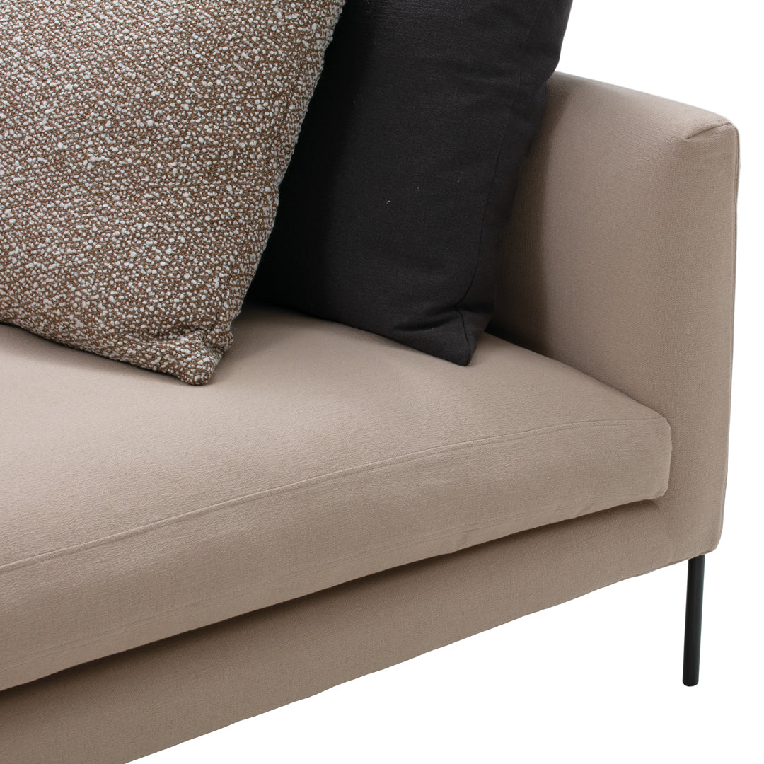 Beige sofa with black and textured brown decorative pillows, showcasing a modern, minimalist design.