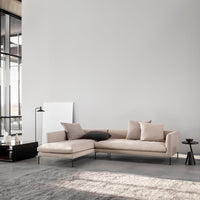 Light beige sectional sofa with plush cushions, black accents, and a minimalist design in a modern setting.