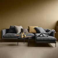 Stylish gray sofa with textured cushions in muted tones against a warm gold wall, perfect for modern interiors.