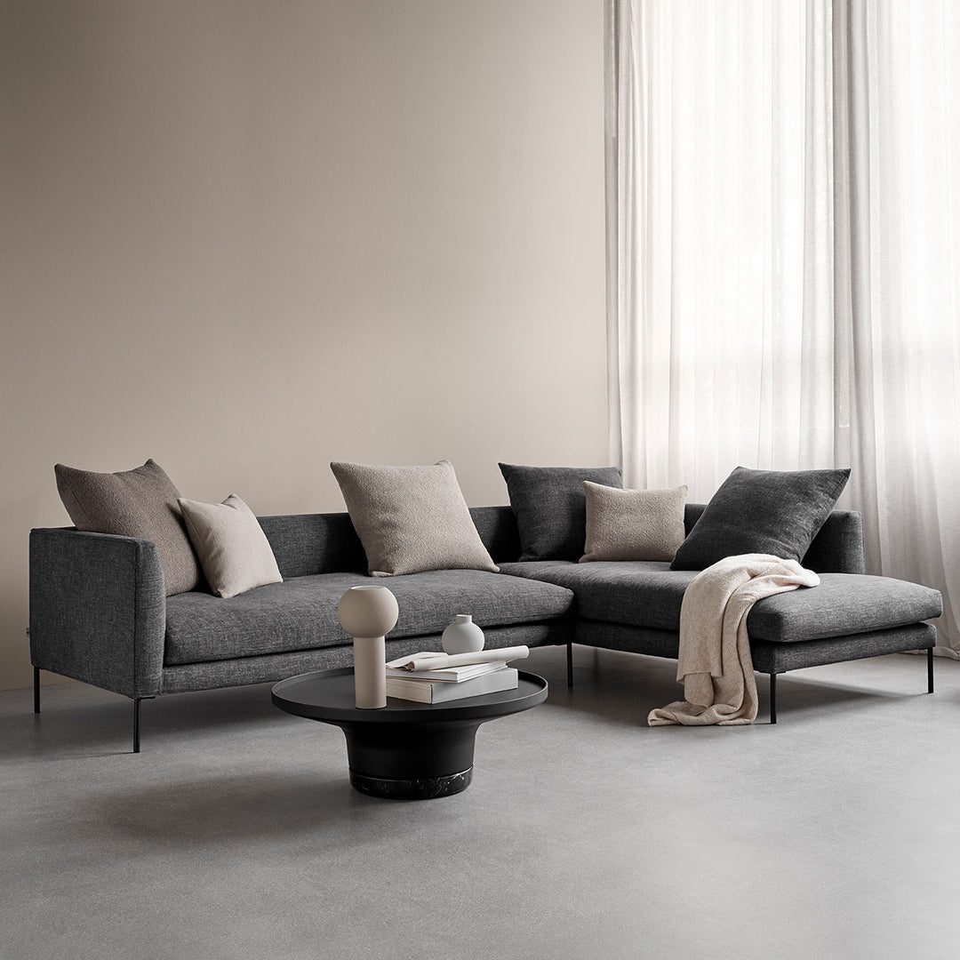 Modern gray sectional sofa with light gray and dark gray cushions, complemented by a black round coffee table.