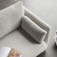 Textured cream upholstery on a modern sofa with a matching pillow, showcasing a soft, minimalist design.