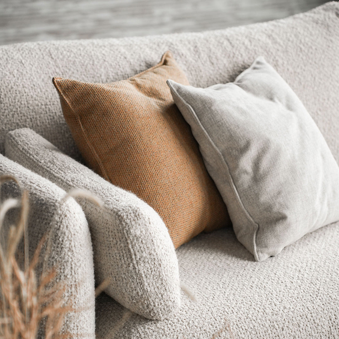 Cozy beige textured couch with a brown and light gray pillow for a warm, neutral home decor accent.