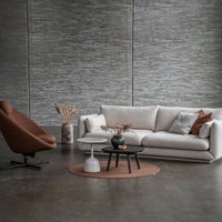 Light gray textured wall with a cream sofa, rust-colored chair, black coffee table, and muted brown accent rug.
