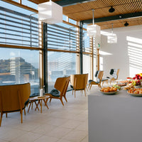 Modern interior with wooden furniture, gray accents, and vibrant fruit display against natural light through striped blinds.