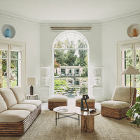 Cozy living room with neutral tones, natural textures, and light wood patterns, overlooking a lush green garden.