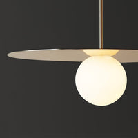 Minimalist pendant light featuring a white globe and sleek metallic plate against a dark background. Elegant modern design.