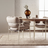Beige textured armchair with soft curves, paired with a light wood table, set on a neutral rug. Elegant and modern design.