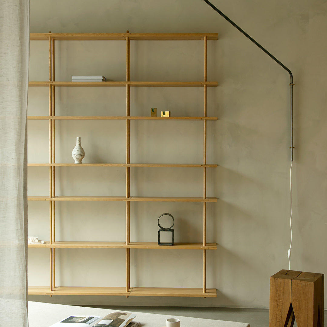 Light wooden shelving unit with clean lines and minimalist design against a muted, textured wall.
