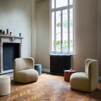 Modern curved chairs in neutral tones, featuring textured fabric, with a warm wooden floor and soft natural light.
