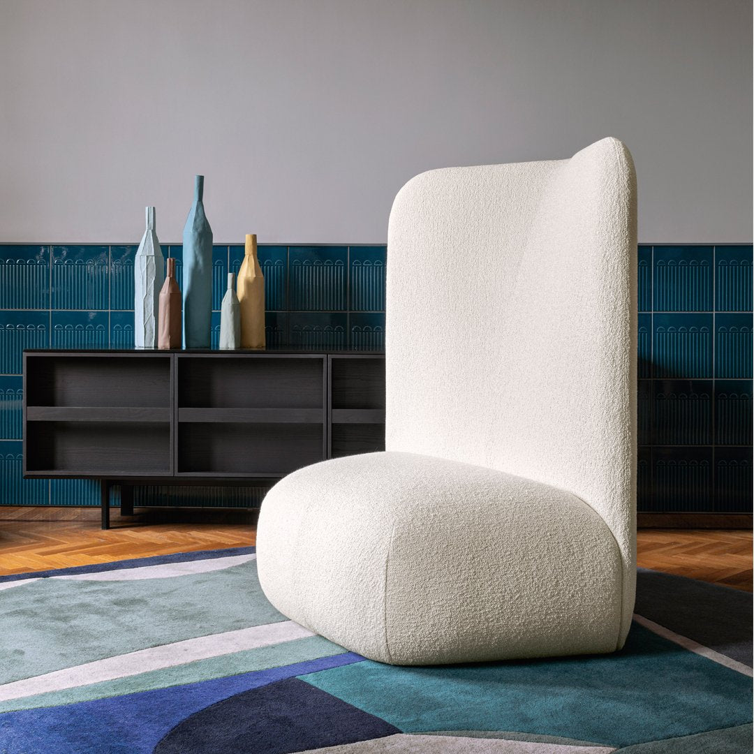 Textured off-white chair on a multicolored geometric rug featuring shades of blue, green, and purple.