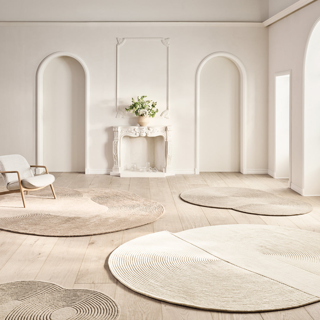 Soft beige and cream circular rugs showcasing subtle textures and delicate patterns on a light wood floor.
