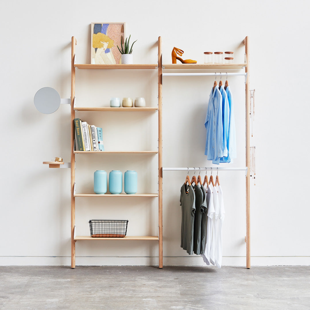Minimalist wooden shelving with light natural tones, soft blue clothing, and pastel decor accents.