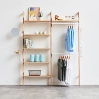 Minimalist wooden shelving with light natural tones, soft blue clothing, and pastel decor accents.