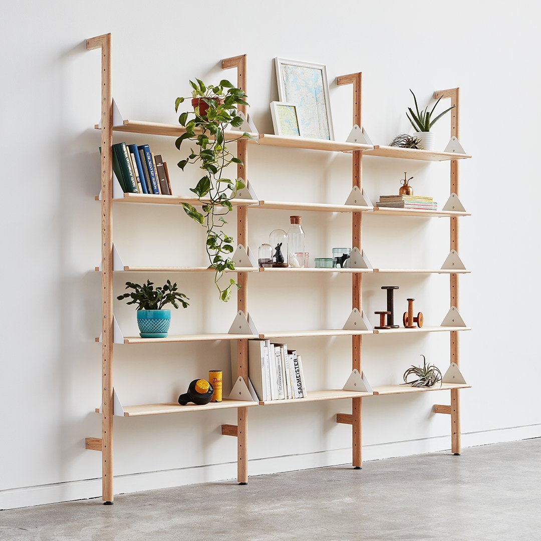 Modern wooden shelving unit with a natural finish, featuring white shelves and geometric plant holders.