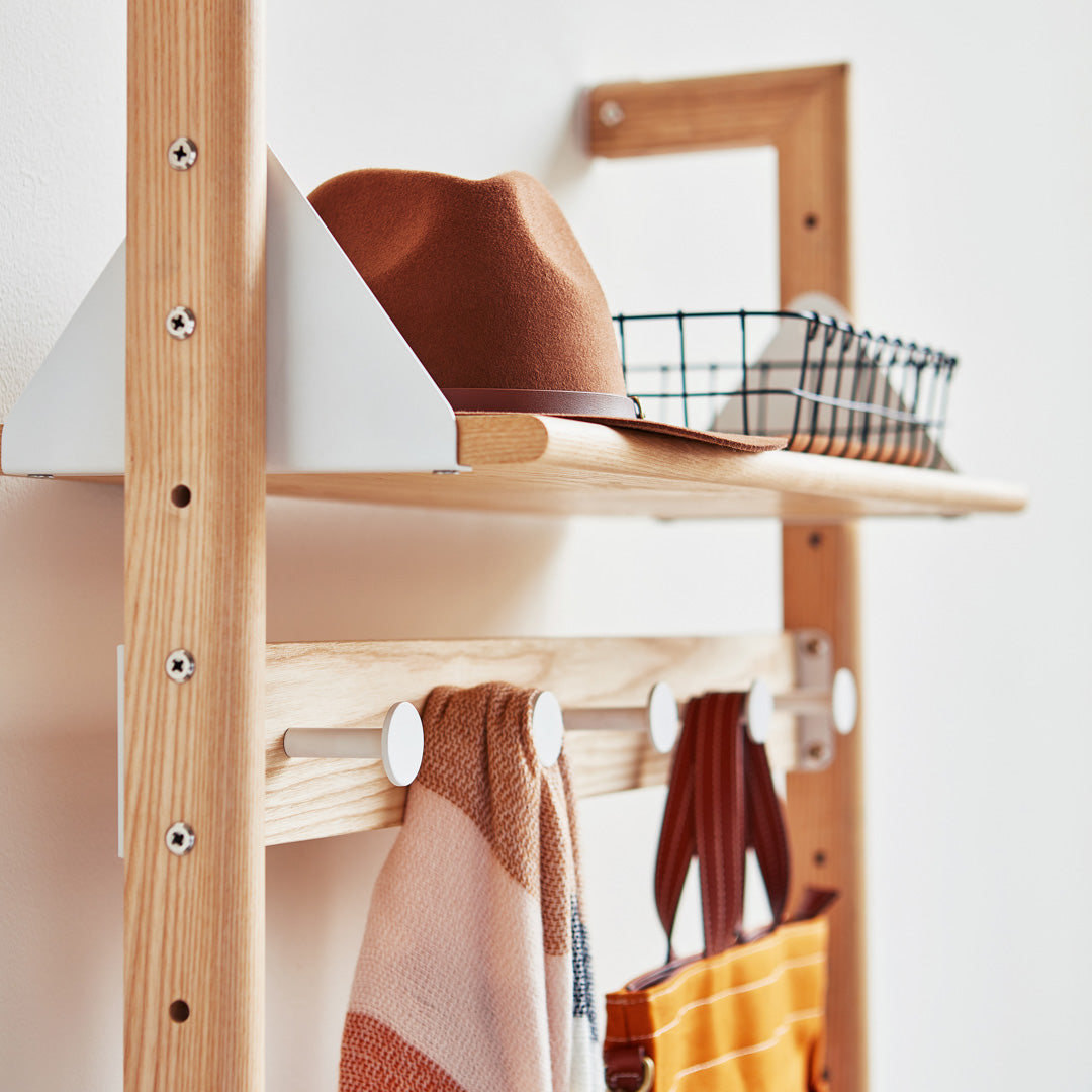 "Natural wood shelf with brown hat, black wire basket, and patterned scarves in warm colors."