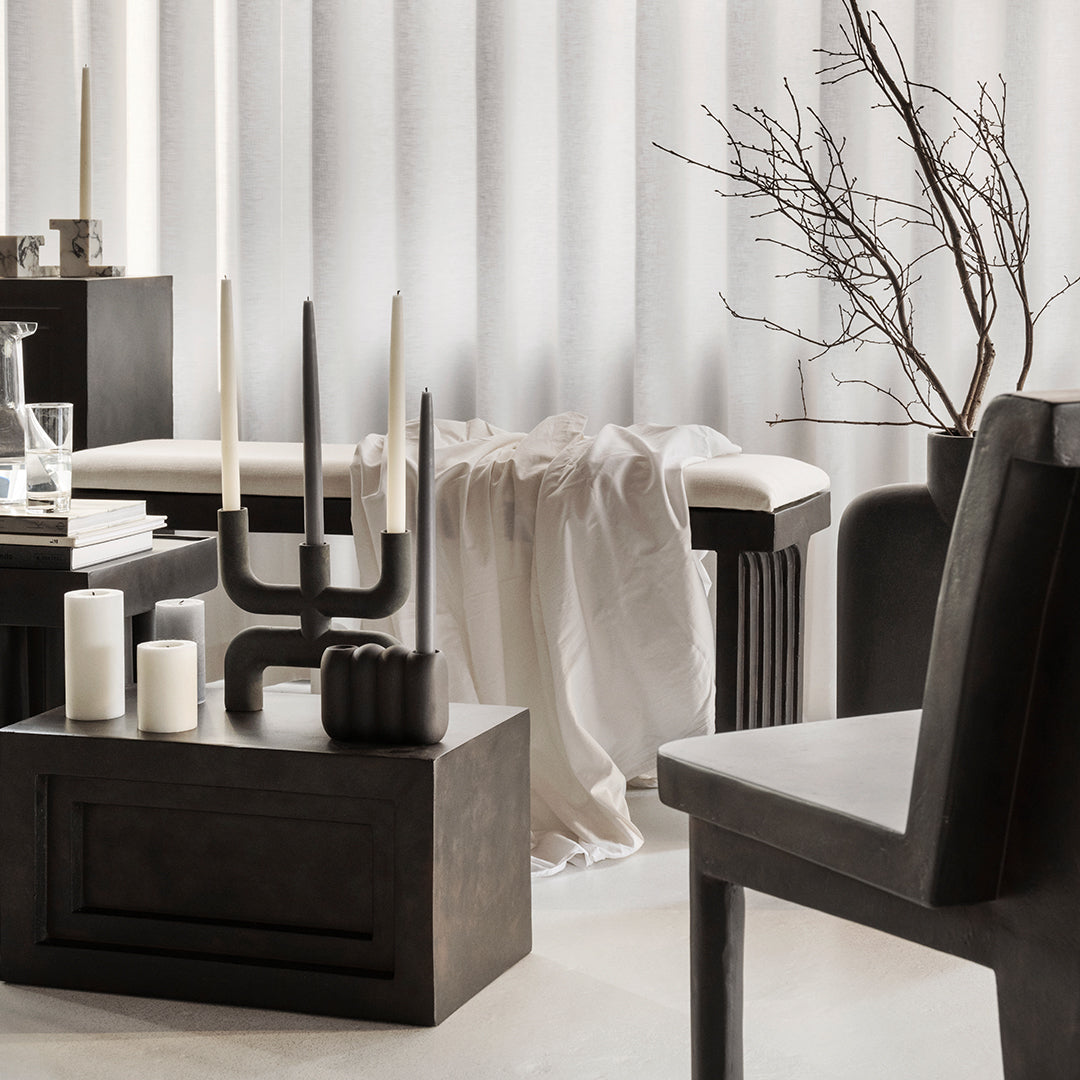 Modern interior featuring neutral tones with black furniture, textured fabrics, and minimalist decor elements.