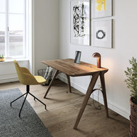 Modern wooden desk with a walnut finish, paired with a vibrant yellow chair, against a neutral-toned room.