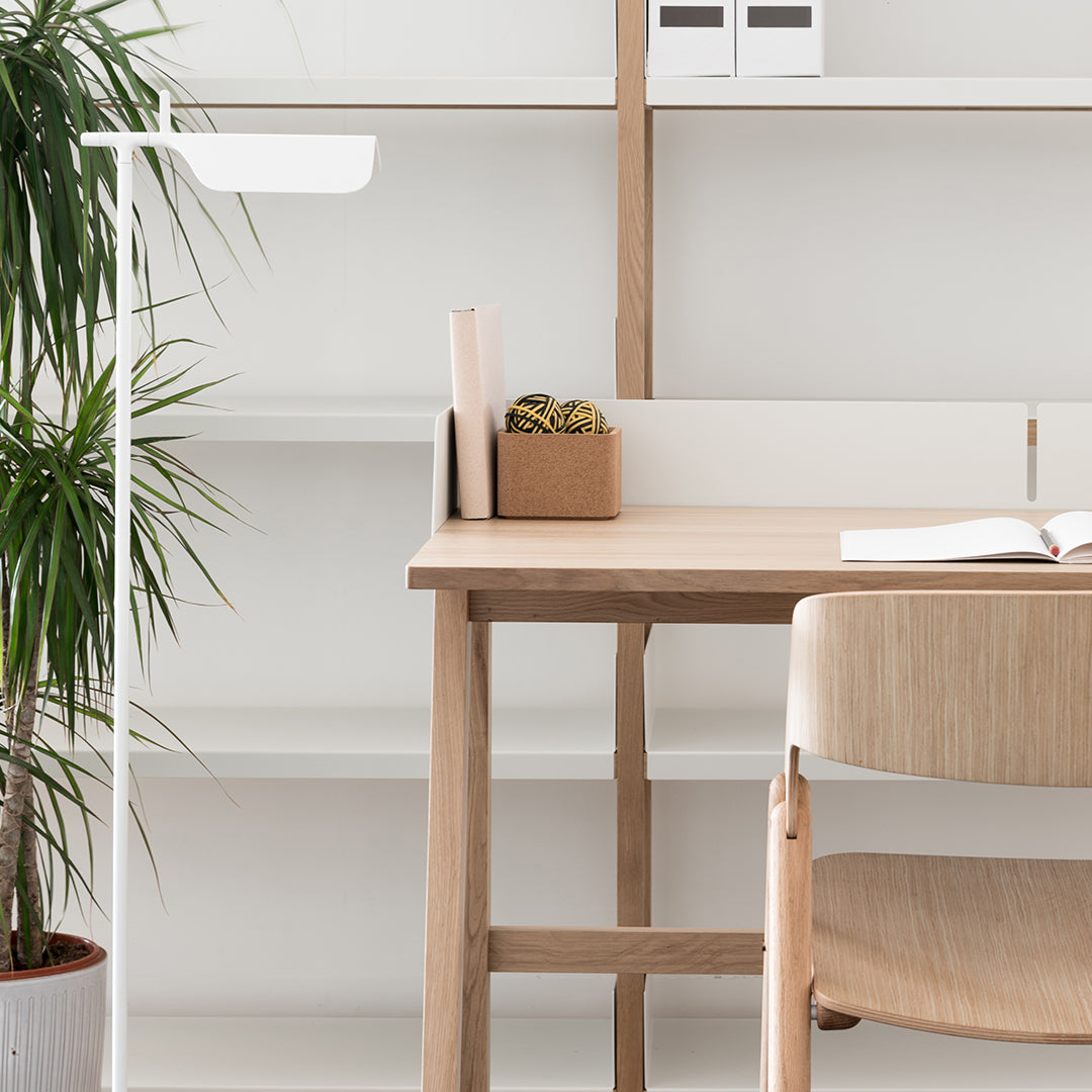 Light wood desk with a natural finish, paired with a soft beige chair against a minimalistic white backdrop.